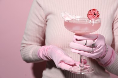 Photo of Woman holding glass of drink on pink background, closeup