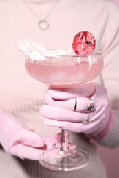 Photo of Woman holding glass of drink on pink background, closeup