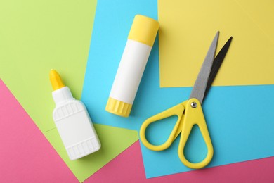 Photo of Glue, colorful paper and scissors on pink background, flat lay