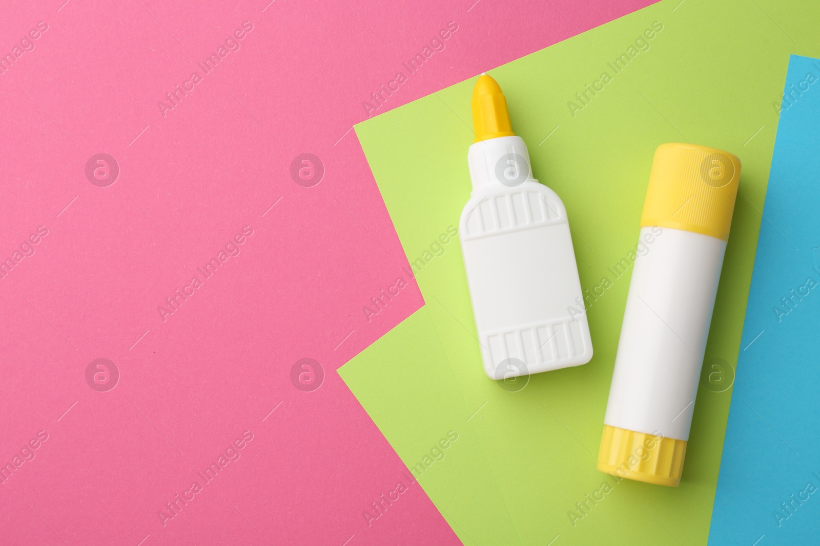 Photo of Glue and colorful paper on pink background, flat lay. Space for text