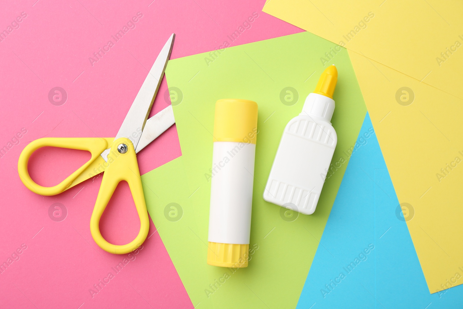 Photo of Glue, colorful paper and scissors on pink background, flat lay