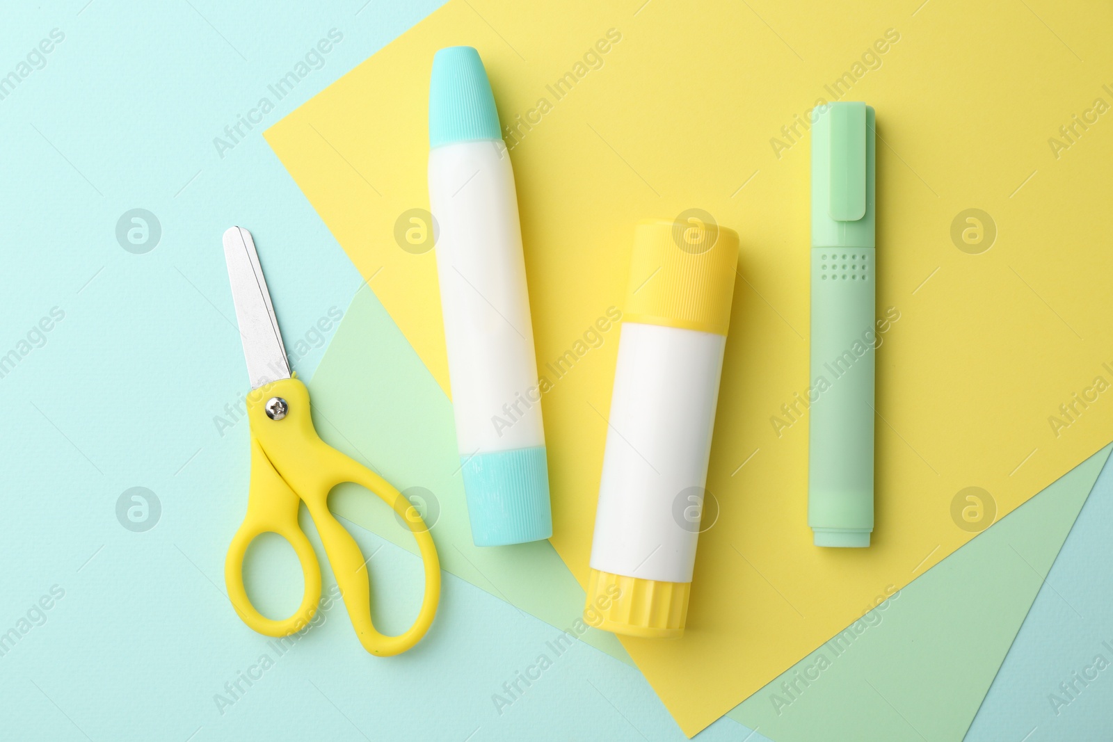 Photo of Glue, colorful paper and scissors on turquoise background, flat lay