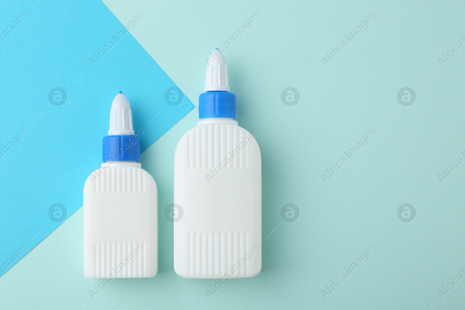 Photo of Bottles of glue on color background, flat lay. Space for text