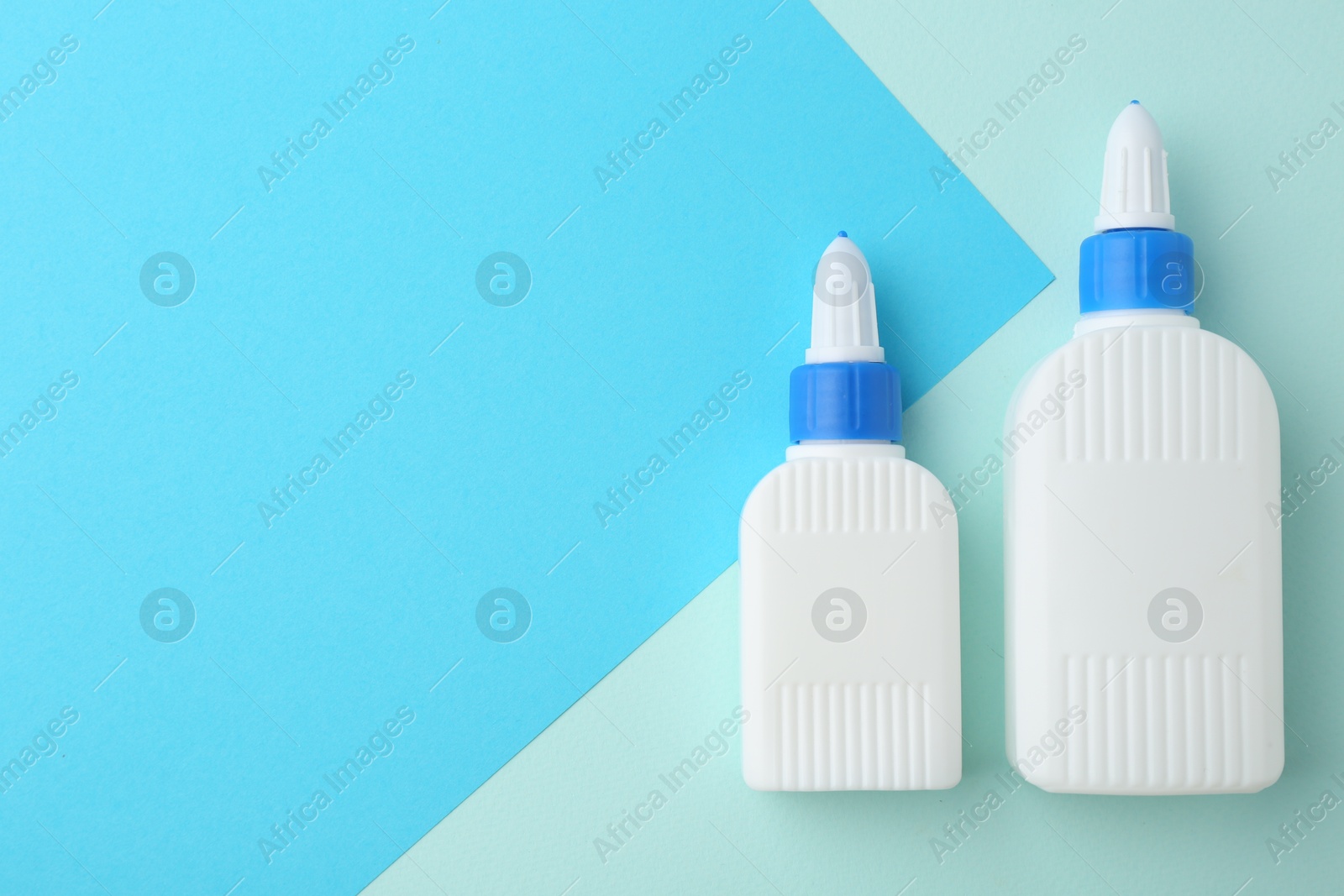 Photo of Bottles of glue on color background, flat lay. Space for text