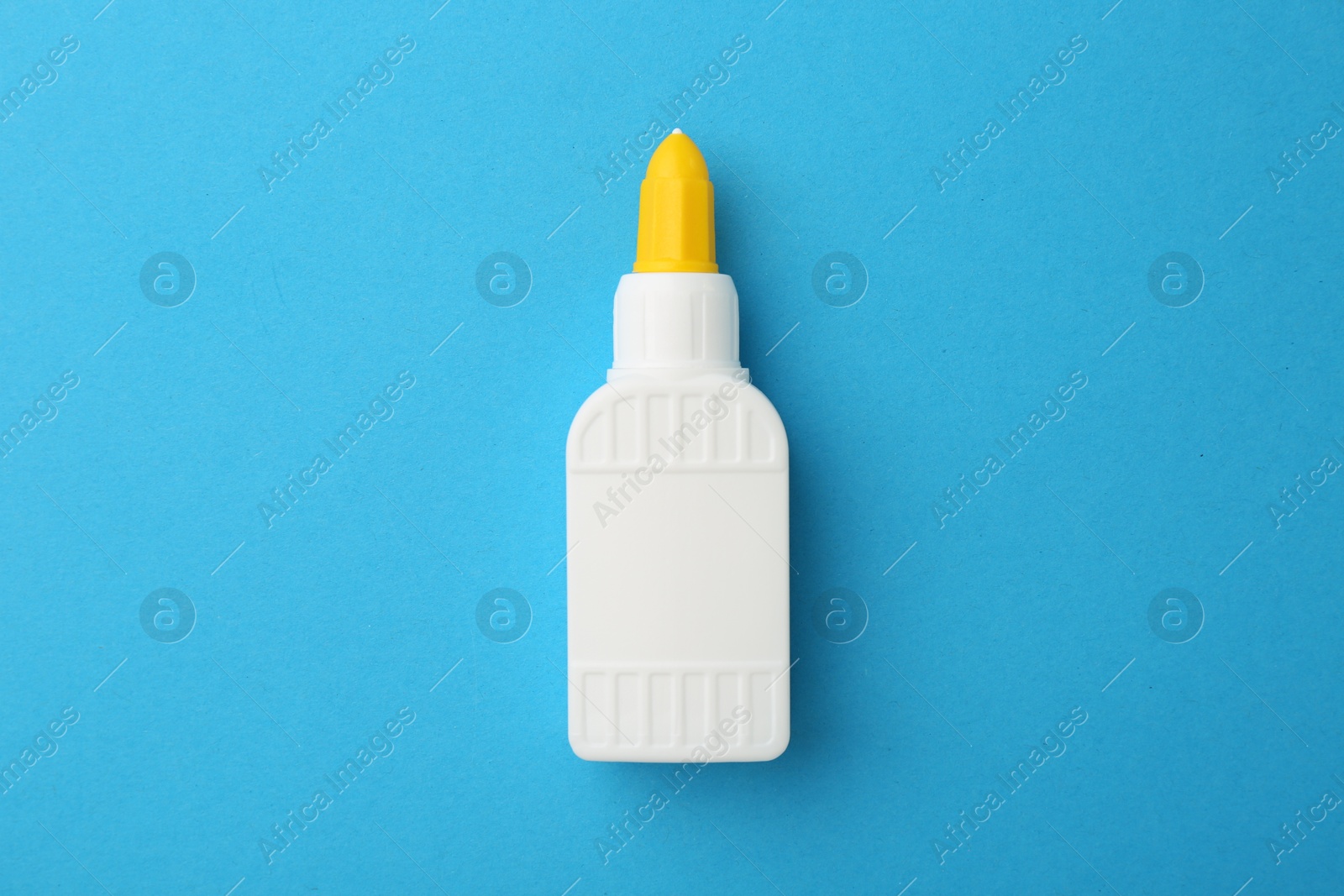 Photo of Bottle of glue on light blue background, top view