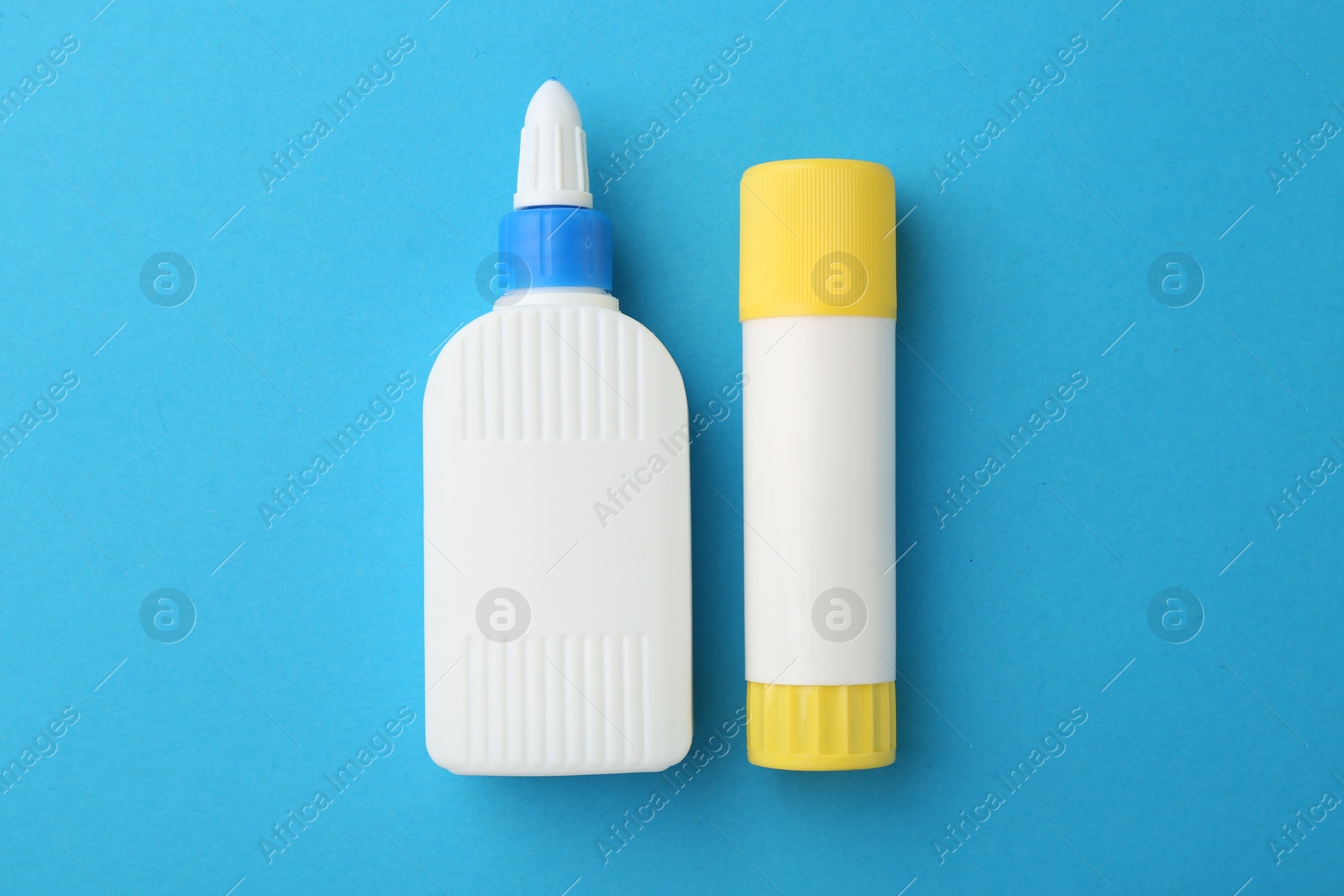 Photo of Different types of glue on light blue background, flat lay