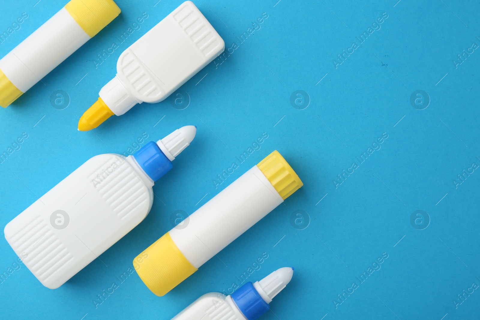 Photo of Different types of glue on light blue background, flat lay. Space for text