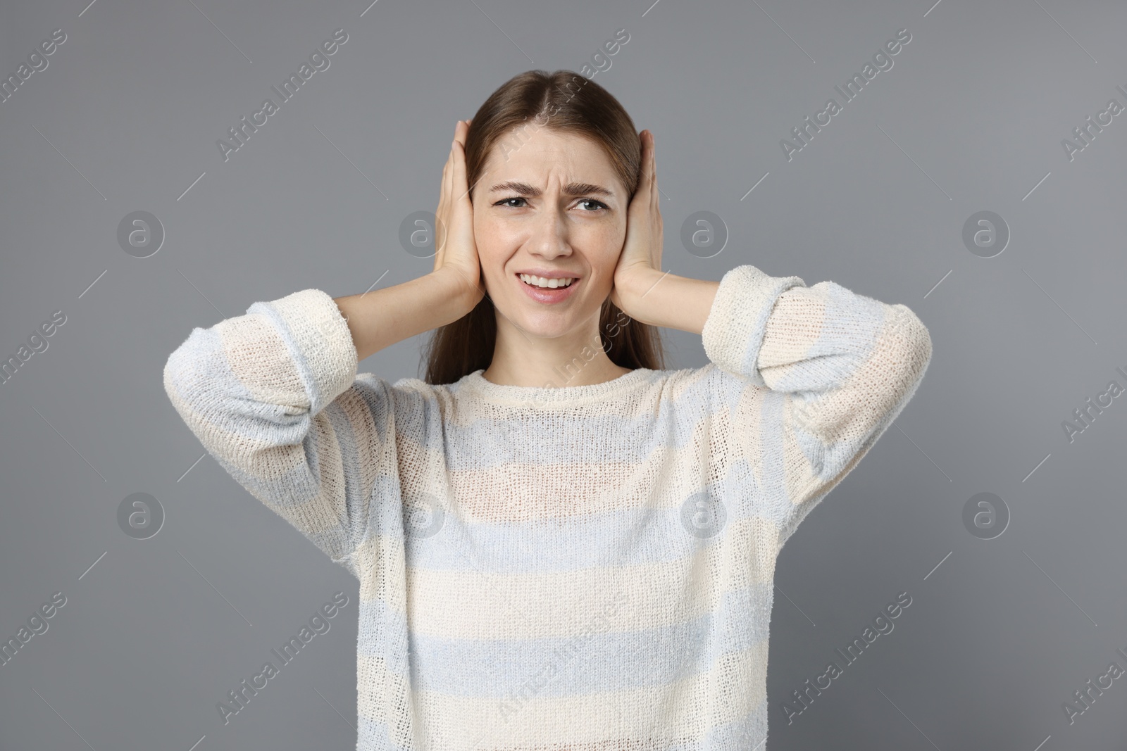 Photo of Woman covering her ears on grey background