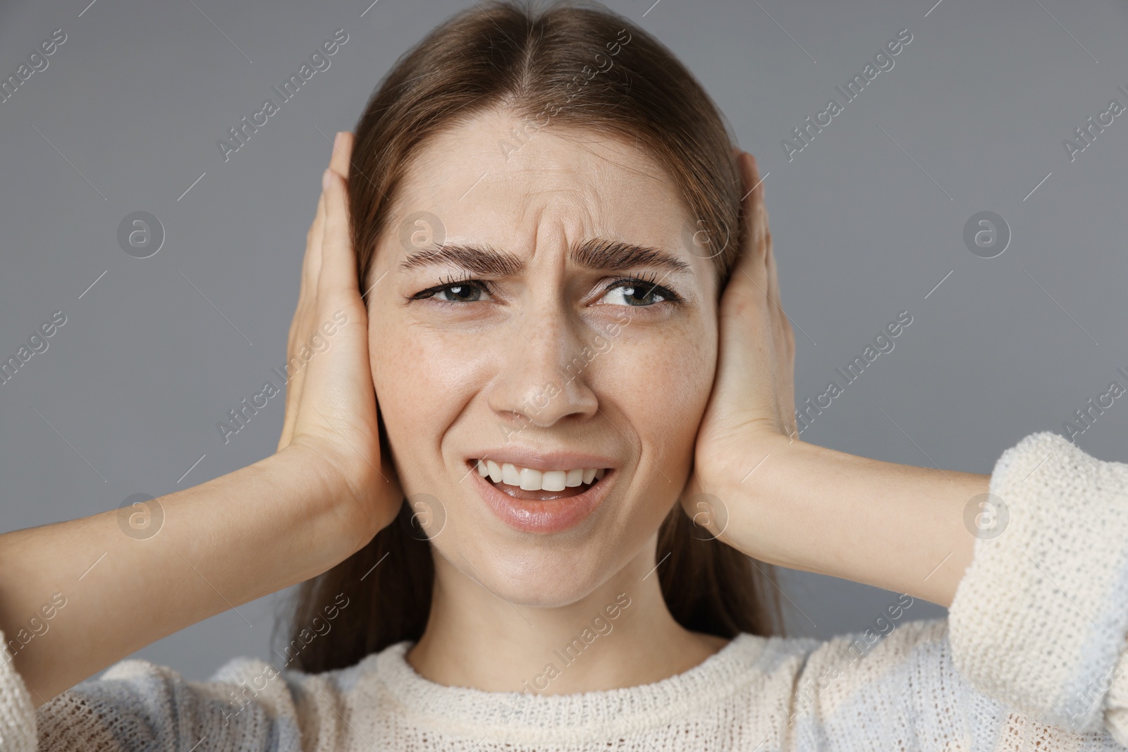 Photo of Woman covering her ears on grey background