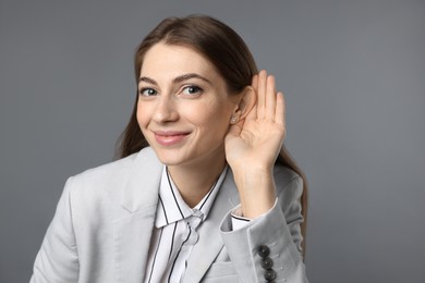 Photo of Woman showing hand to ear gesture on grey background