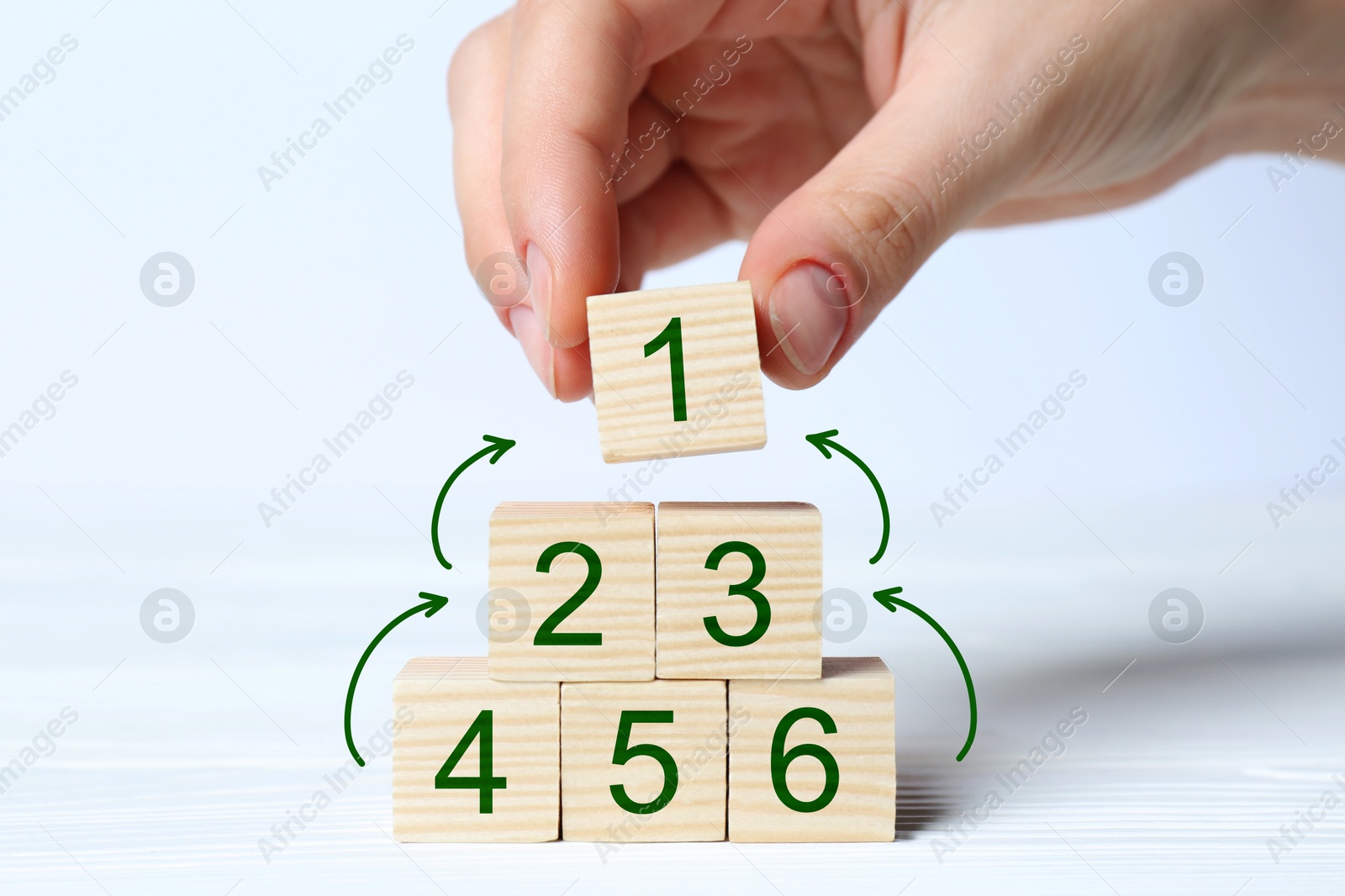 Image of Woman building pyramid of numbered cubes on white background, closeup. Arrows showing direction. Step-by-step concept