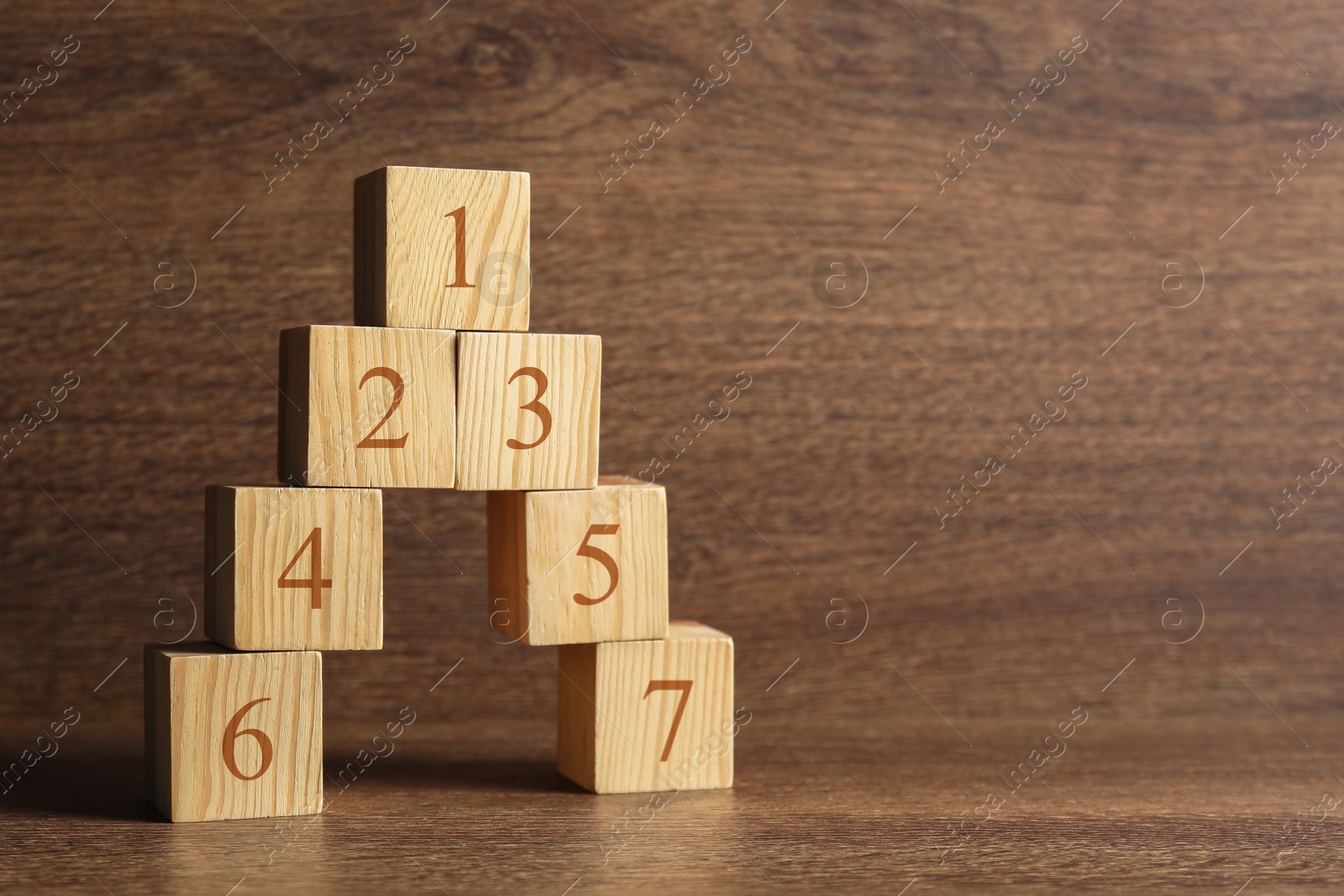 Image of Pyramid of numbered cubes on wooden background. Step-by-step concept