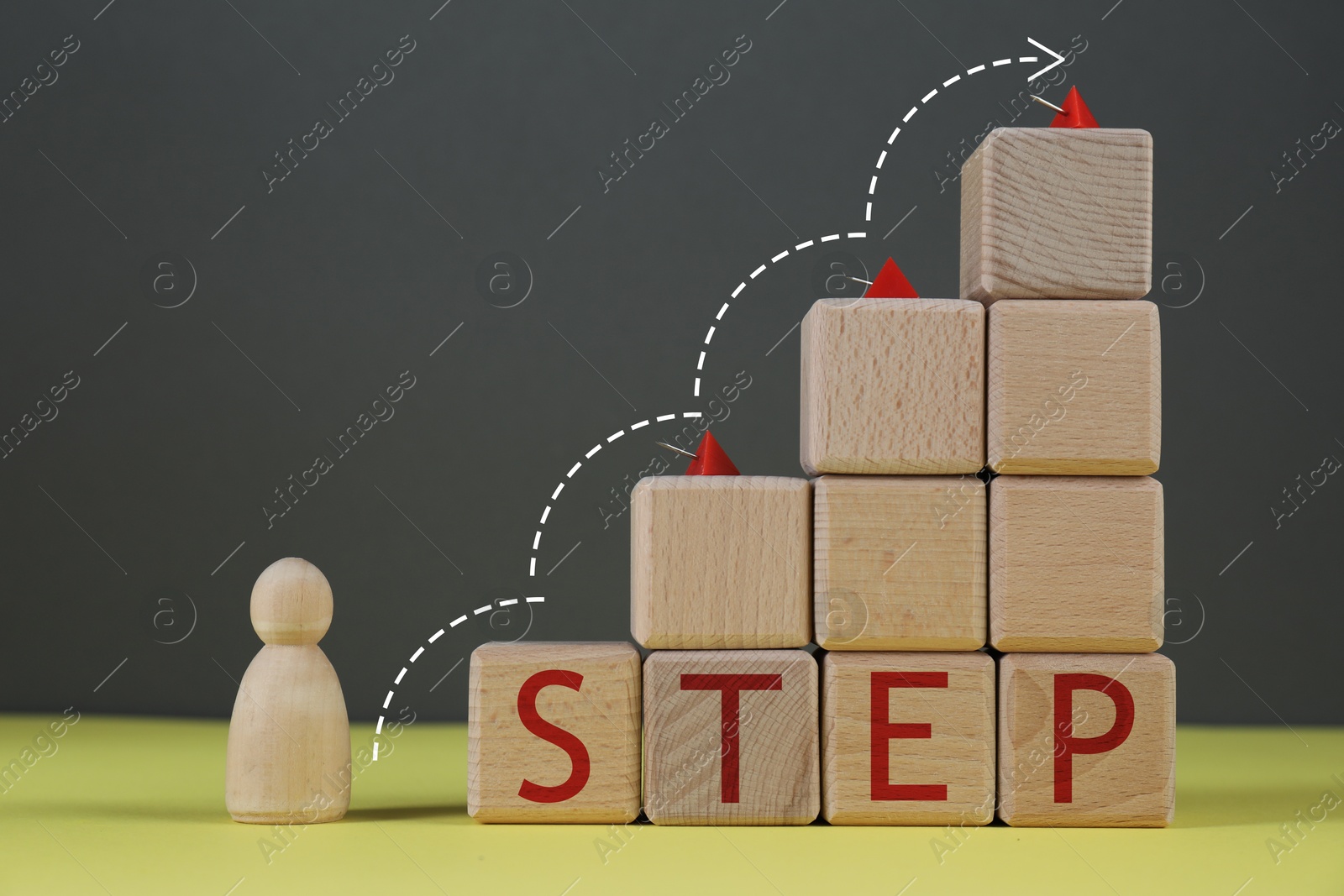 Image of Human figure in front of wooden cubes stair with pins and word Step on yellow table. Arrow showing direction. Step-by-step concept