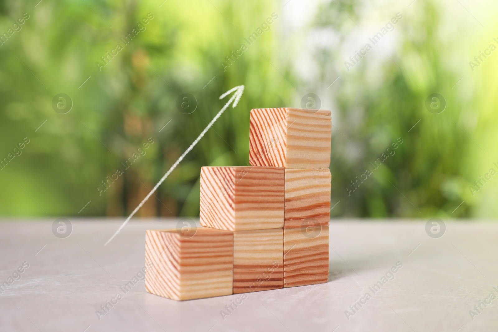 Image of Stair of wooden cubes and arrow on grey table. Step-by-step concept