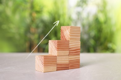 Image of Stair of wooden cubes and arrow on grey table. Step-by-step concept