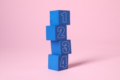 Image of Stacked blue cubes with numbers from 1 to 4 on pink background. Step-by-step concept