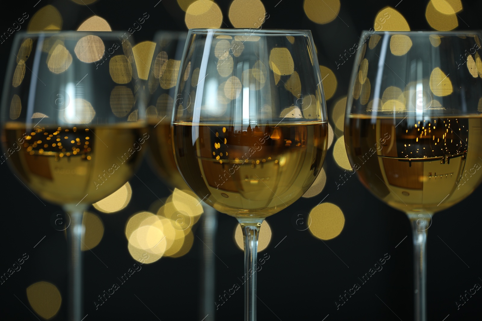 Photo of Glasses of luxury white wine against blurred lights, closeup. Bokeh effect