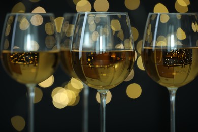 Glasses of luxury white wine against blurred lights, closeup. Bokeh effect