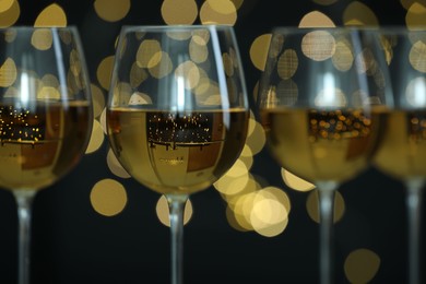 Photo of Glasses of luxury white wine against blurred lights, closeup. Bokeh effect