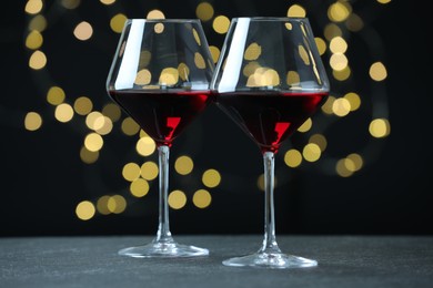 Photo of Glasses of luxury red wine on table against blurred lights. Bokeh effect