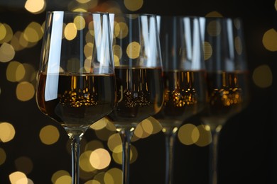 Photo of Glasses of luxury white wine against blurred lights, closeup. Bokeh effect