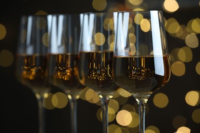 Photo of Glasses of luxury white wine against blurred lights, closeup. Bokeh effect