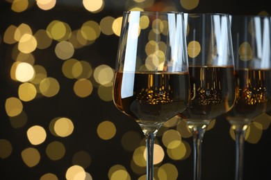 Photo of Glasses of luxury white wine against blurred lights, closeup. Bokeh effect