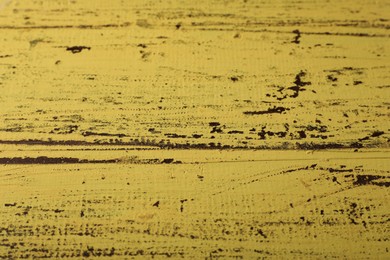 Photo of Old yellow wooden surface with scratches as background, closeup