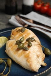 Photo of Delicious cooked chicken fillet with capers and lemon slice on plate, closeup