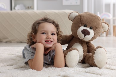 Photo of Cute little girl with teddy bear on floor at home