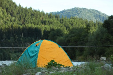 Photo of Colorful camping tent on stones in mountains