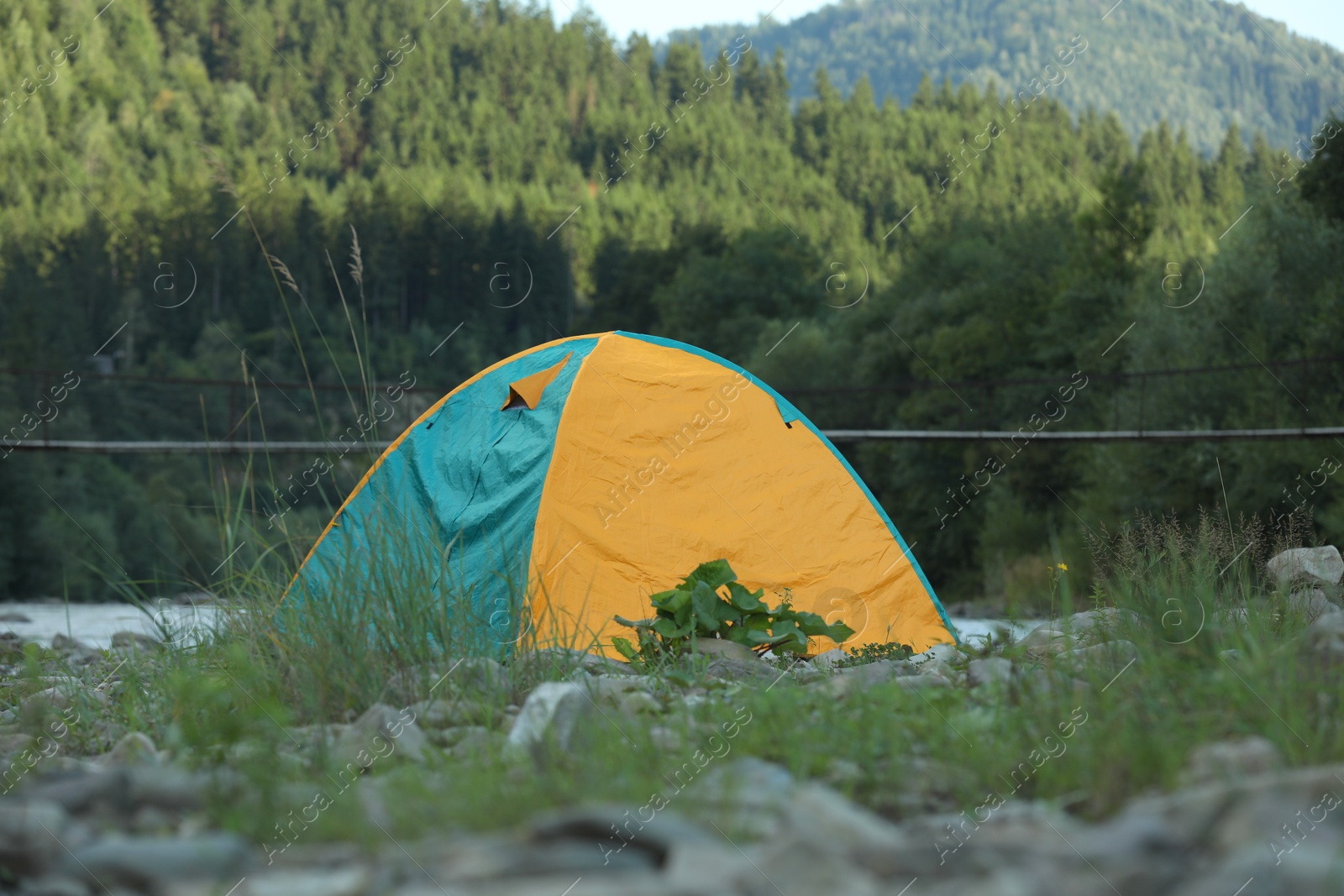 Photo of Colorful camping tent on stones in mountains