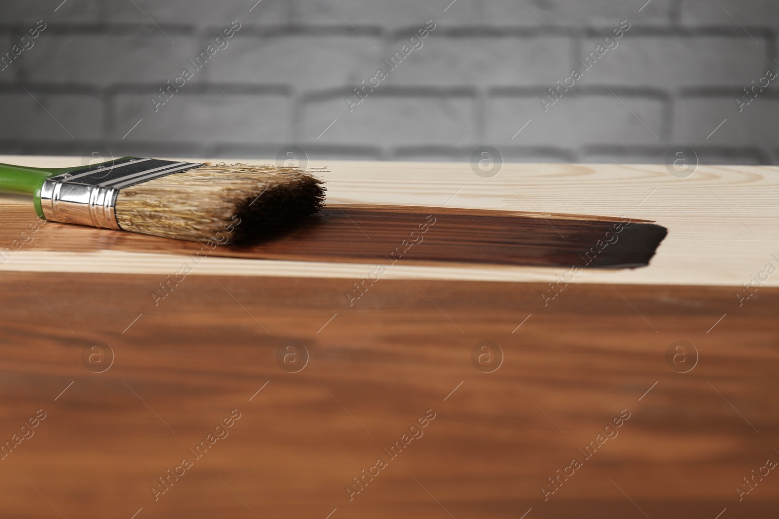 Photo of Applying walnut wood stain. Brush on wooden surface, closeup