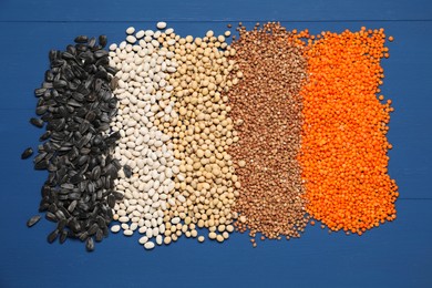 Photo of Different types of cereals, legumes and seeds on blue wooden table, flat lay