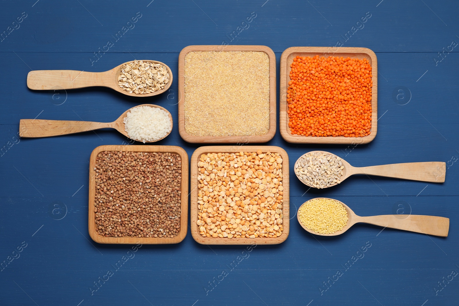 Photo of Different types of legumes and cereals on blue wooden table, flat lay