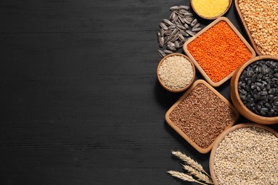 Photo of Different types of seeds, legumes and cereals on black wooden table, flat lay. Space for text