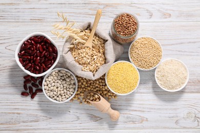 Different types of legumes and cereals on white wooden table, flat lay