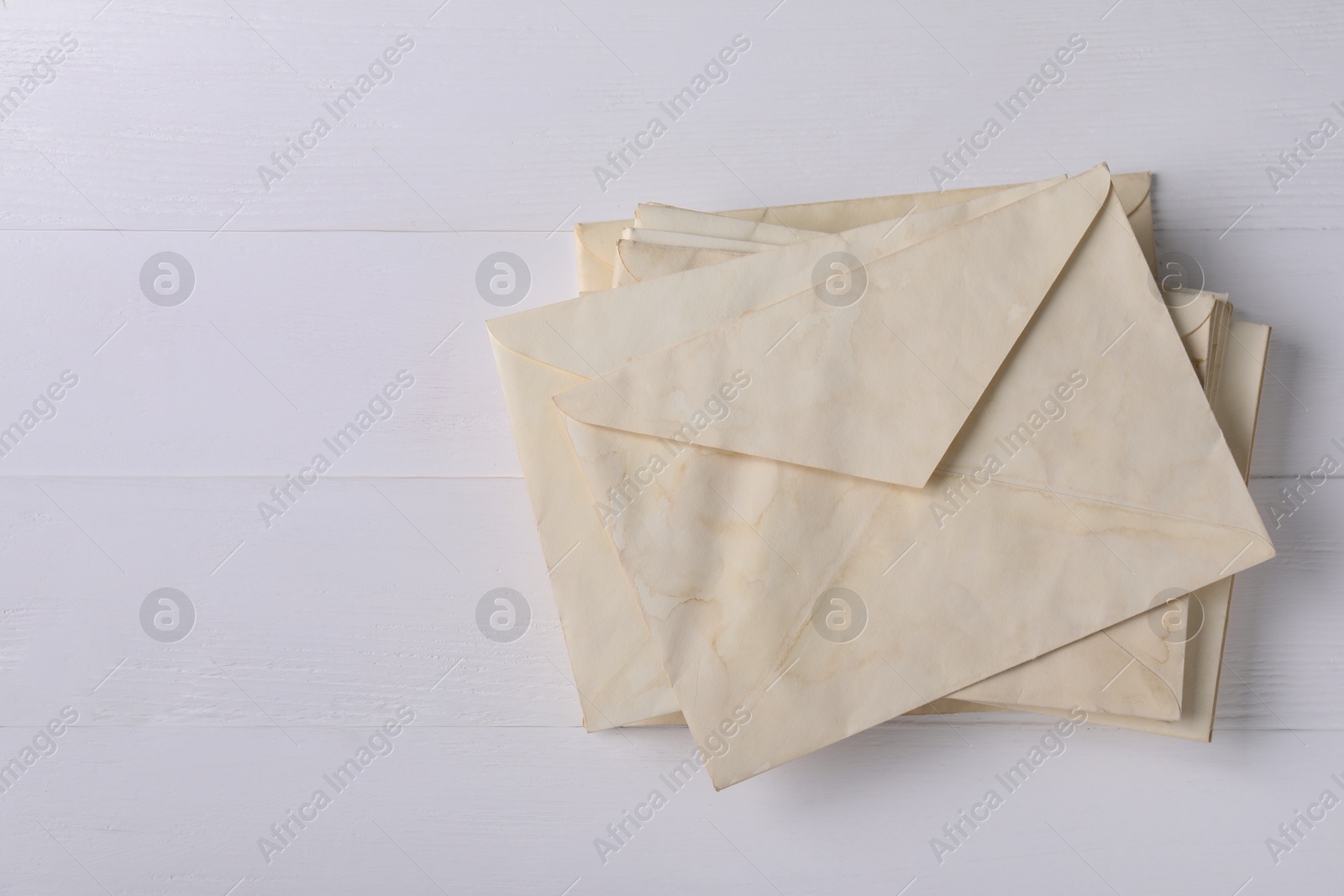 Photo of Stack of old letter envelopes on white wooden table, top view. Space for text