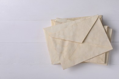 Photo of Stack of old letter envelopes on white wooden table, top view. Space for text