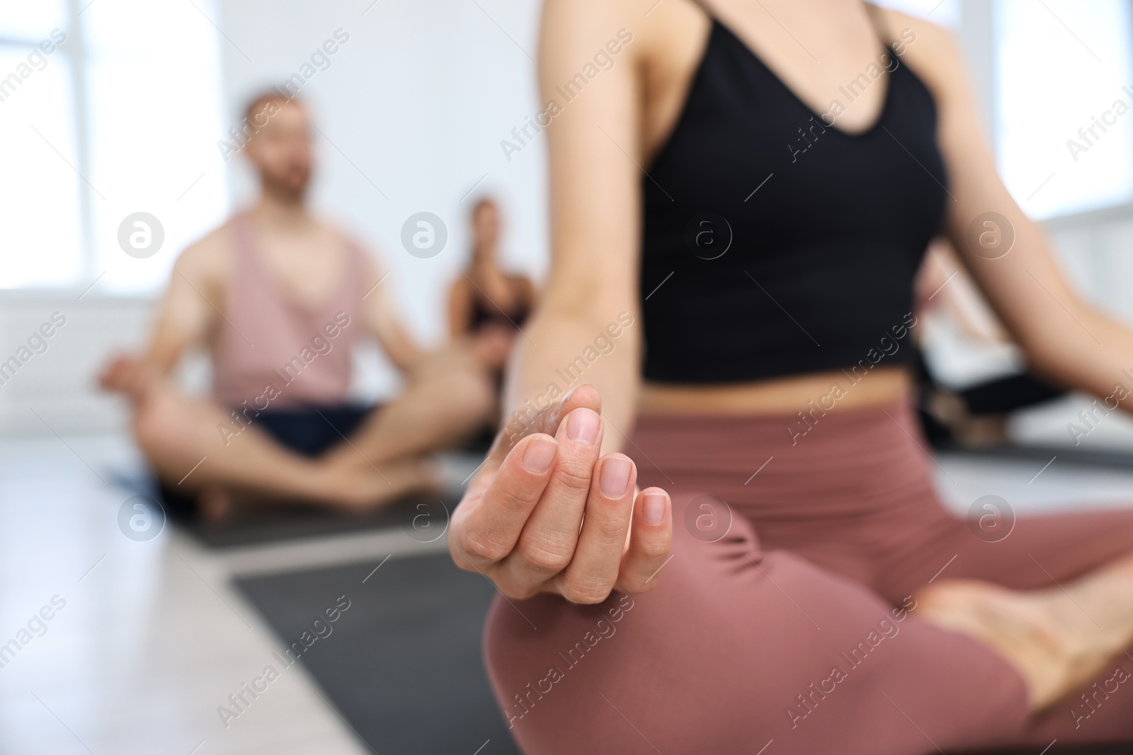 Photo of Group of people meditating on mats in yoga class, closeup