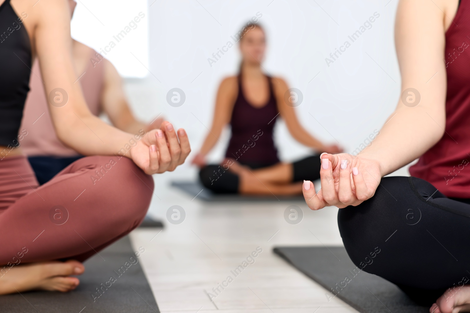 Photo of Group of people meditating on mats in yoga class, closeup