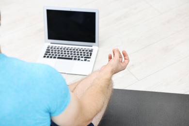 Man meditating near laptop at home, closeup