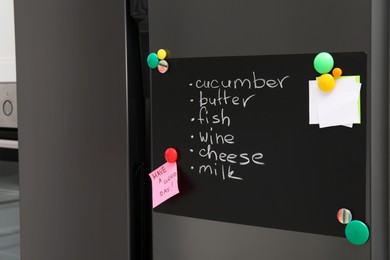 Photo of Magnetic board with shopping list and notes on refrigerator in kitchen