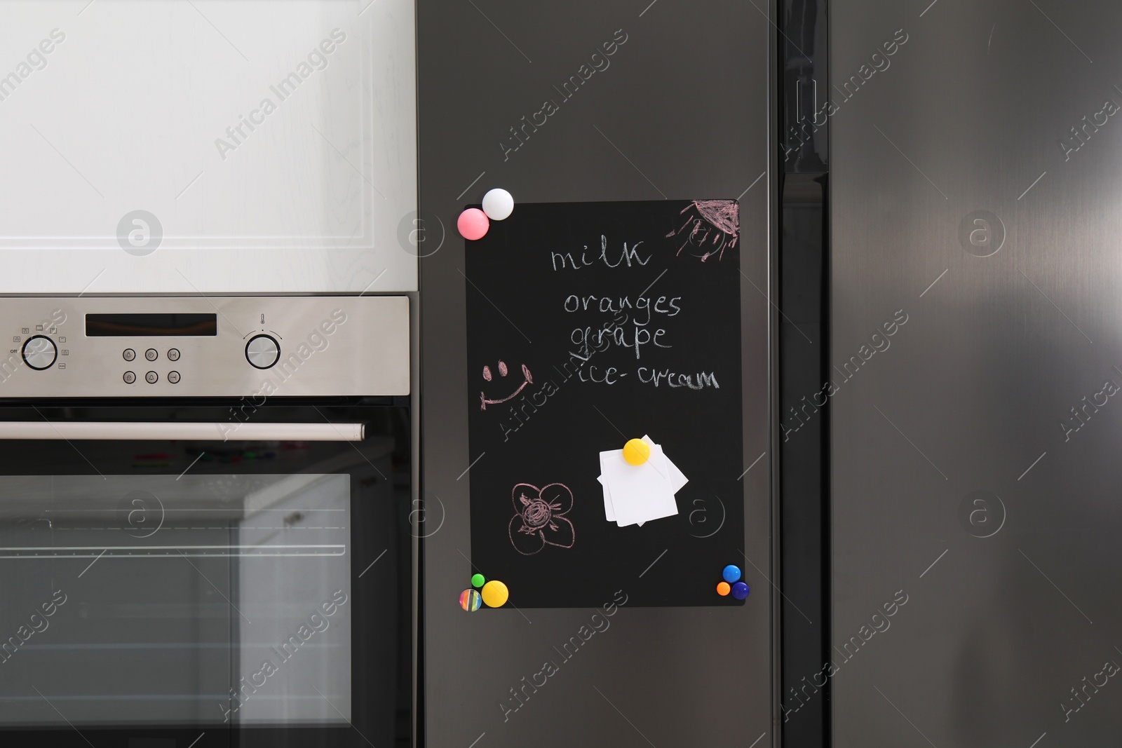 Photo of Magnetic board with shopping list and notes on refrigerator in kitchen