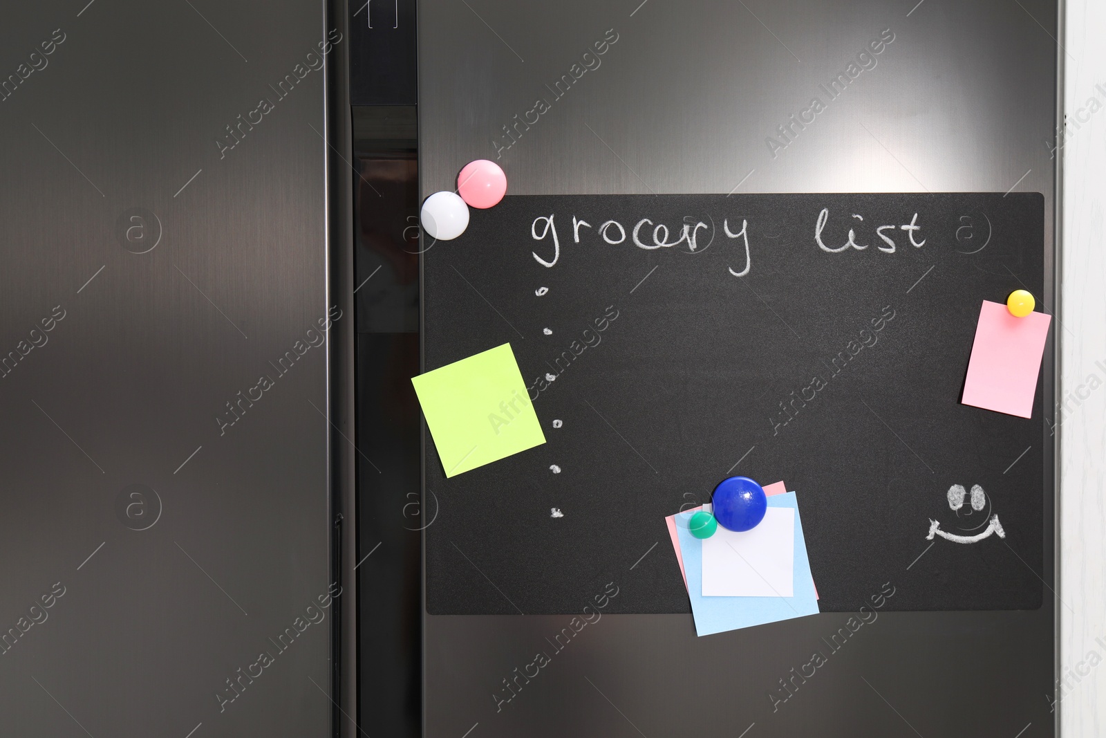 Photo of Magnetic board with grocery list and notes on refrigerator in kitchen