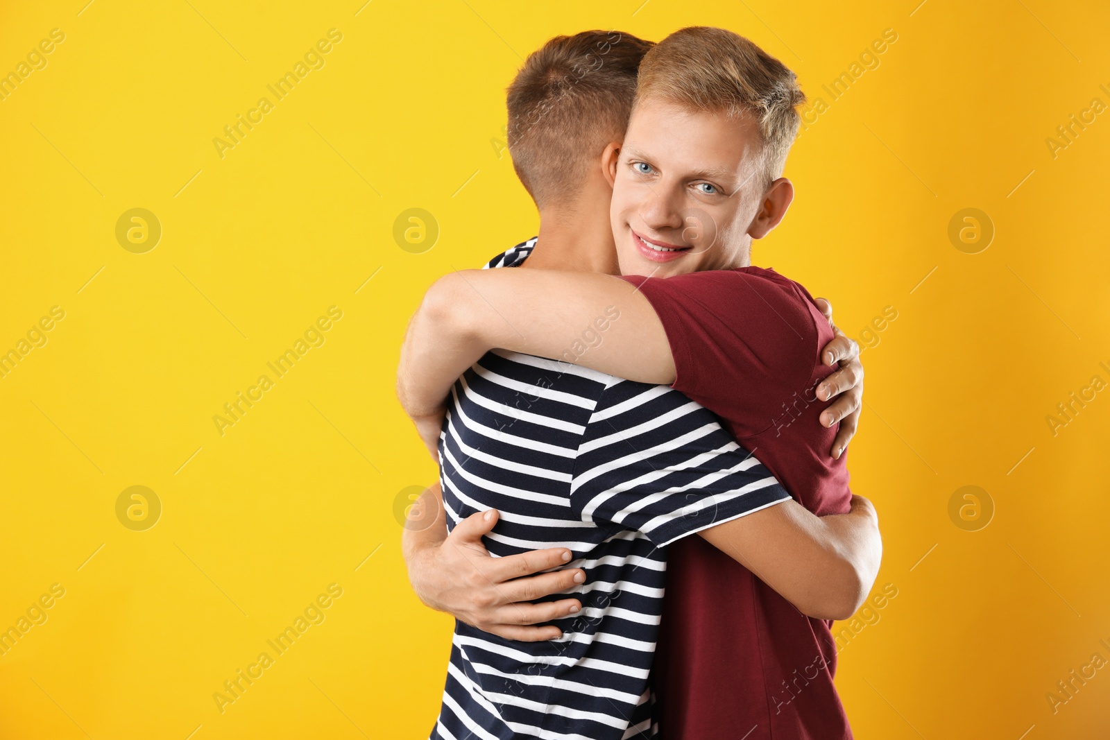 Photo of Happy brothers hugging on orange background. Space for text