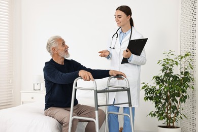 Doctor consulting senior patient with walking frame in hospital ward