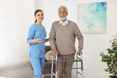 Nurse helping senior man with walking frame in clinic