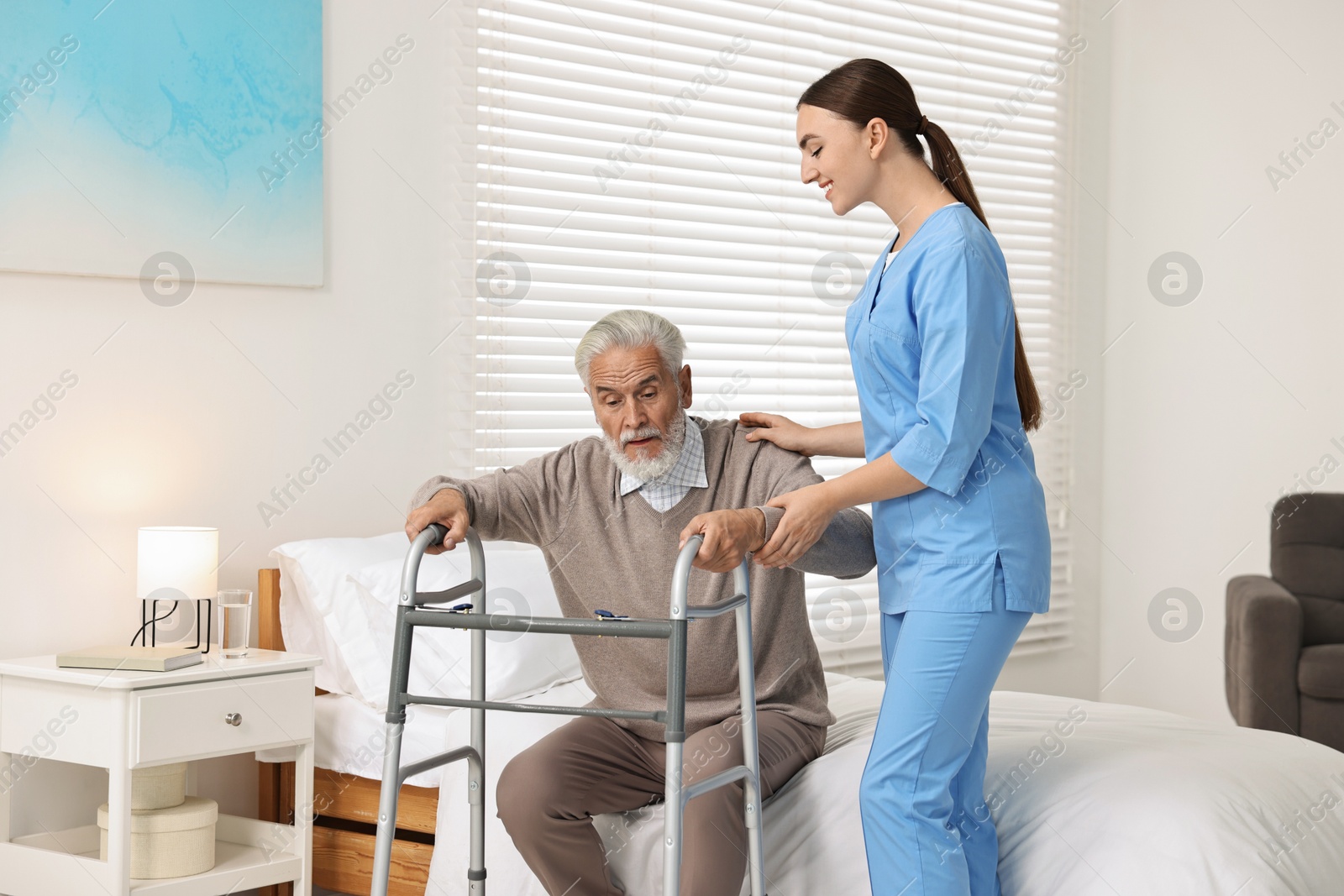 Photo of Nurse helping senior man with walking frame in clinic