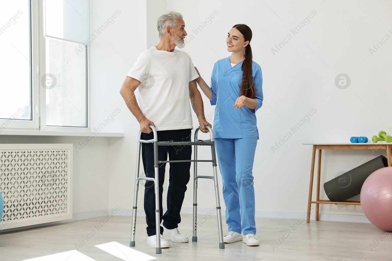 Photo of Nurse helping senior man with walking frame in clinic